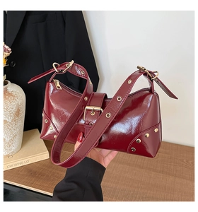 Détail du sac bandoulière en cuir verni rouge foncé avec œillets métalliques dorés