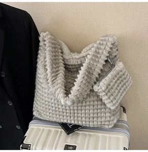 Detailed view of plush quilted tote bag with matching pouch on a travel suitcase