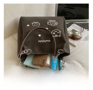 Dettaglio degli ampi interni della borsa tote in pelle marrone con ricamo a gatto e oggetti