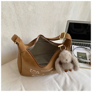 Detalle de bolso hobo marrón con estampado de dibujos, colgante de conejo y cremallera