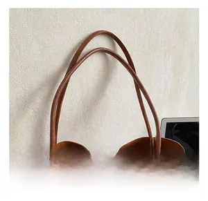 Close-up of vintage brown leather tote bag showing slim handles and decorative charm