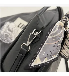 Détail d'un sac à main en cuir noir brillant avec garniture argentée et anse foulard soie