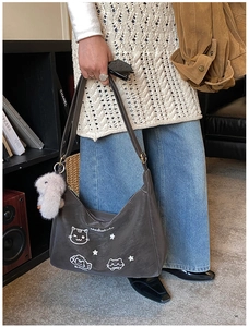 Detalle de bolso tote de ante gris con bordado de gato y colgante de conejo peluche