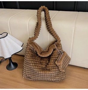 Detail of a brown plush tote bag with a matching mini pouch on a stylish sofa background