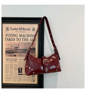 Détail du sac bandoulière en cuir verni bordeaux avec rivets vintage et boucle de sangle