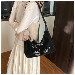 Detalle del bolso de hombro creciente negro con estampado de gato y colgante de conejo