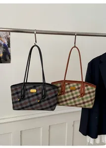 Détail de sacs fourre-tout à carreaux avec poignées en cuir et plaque logo en métal