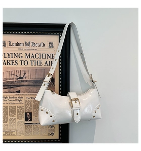 Détail du sac d'épaule en cuir verni blanc avec boucles dorées et rivets style Y2K