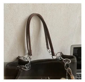 Dettaglio della borsa tote marrone opaco con anelli in metallo argento e logo ricamato