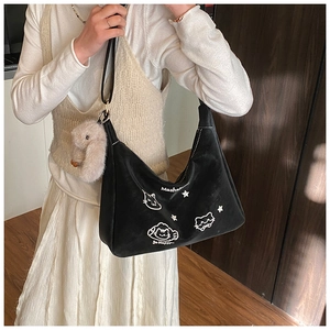 Detalle de bolso hobo negro con bordado de gato blanco y colgante de conejo de peluche