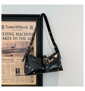 Détail d'un sac sous le bras noir brillant avec clous dorés et boucle de luxe