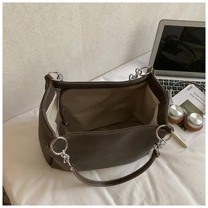 Dettaglio della grande borsa tote marrone scuro con cuciture e manici ad anello in metallo