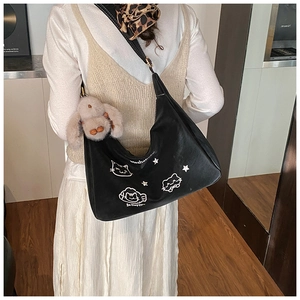 Detalle del bolso hobo negro con estampados de gatos blancos y un colgante de conejo suave