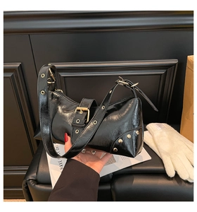 Détail du sac bandoulière en cuir verni noir brillant avec rivets et boucles dorés