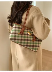 Détail du sac cabas à carreaux avec lanières en cuir porté sur un mannequin en manteau