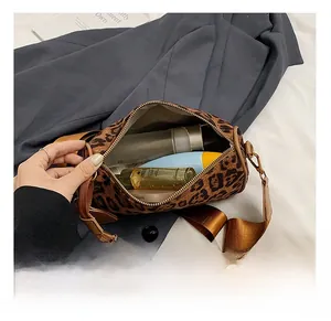 Macro view of leopard print cylinder bag showing spacious interior with wide strap