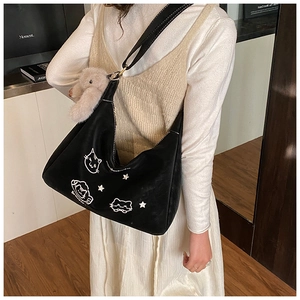 Detalle del bolso hobo negro con bordado de gato, tachuelas estrella y conejo peluche