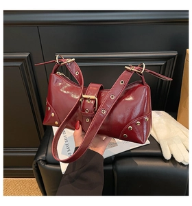 Détail du sac à bandoulière bordeaux avec boucle en métal doré et rivets style punk