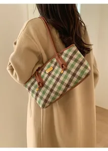 Détail du sac cabas à damier rétro avec bordure en cuir marron et plaque logo dorée