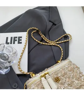 Gros plan du sac bandoulière en tweed avec fermetures fleur dorée et chaîne en métal
