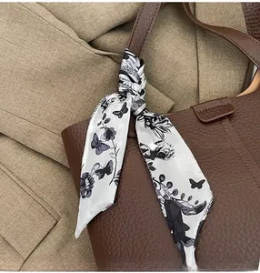 Detail of silk scarf with butterfly pattern tied on a dark brown leather tote handle