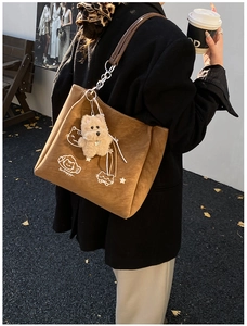 Borsa tote in camoscio marrone con ricamo di gatto e ciondolo a forma di orso in un parco