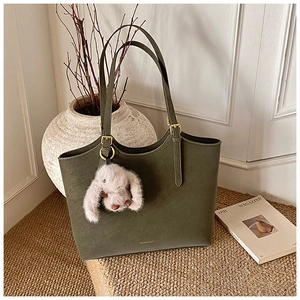Detail of dark green matte leather tote bag with gold buckle and fluffy rabbit charm