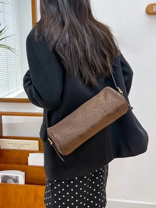 Cylindrical brown leopard print shoulder bag with matte texture and gold buckle
