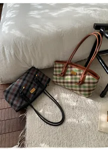 Détail de sacs cabas à carreaux rétro avec texture laine et anses cuir sur literie blanche