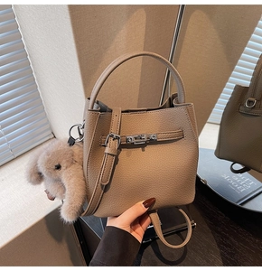 Dettaglio borsa a secchiello taupe in pelle con cinturino a chiusura e charm coniglio
