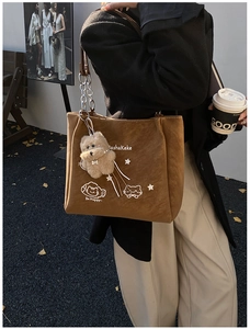 Dettaglio borsa tote in pelle scamosciata marrone con catena e stampa gatto carino