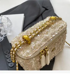 Détail de la texture en tweed avec paillettes et chaîne dorée du mini sac boîte