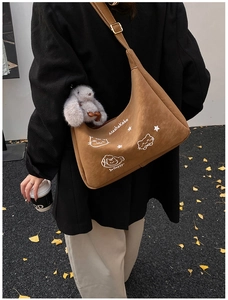 Detalle del bolso hobo marrón mate con estampado de gato y colgante de conejo de peluche