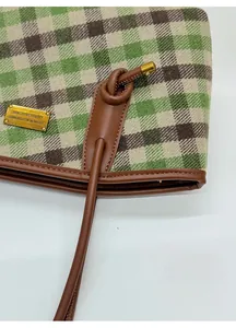 Détail du cabas à carreaux montrant le tissu damier vert et le nœud de poignée en cuir