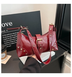 Détail du sac à épaule bordeaux en cuir verni avec rivets punk et grande boucle