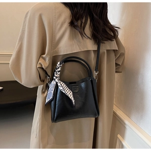 Detail of black PU leather bucket bag with decorative scarf and detachable shoulder strap