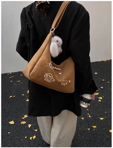 Bolso bandolera de ante marrón con diseño de gato y pompón blanco sobre modelo