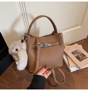 Dettaglio borsa a secchiello marrone in pelle con chiusura argento e ciondolo peluche