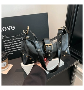 Détail du sac à bandoulière punk avec rivets métalliques dorés et boucle sur cuir noir