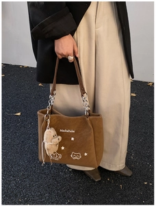 Dettaglio della borsa tote marrone con illustrazione di gatto e ciondolo di peluche