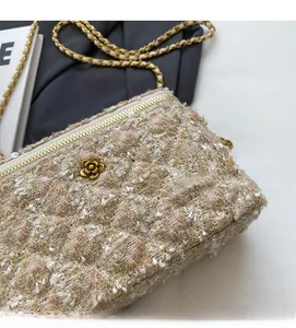 Détail du sac bandoulière en tweed beige avec fleur dorée et bandoulière chaîne