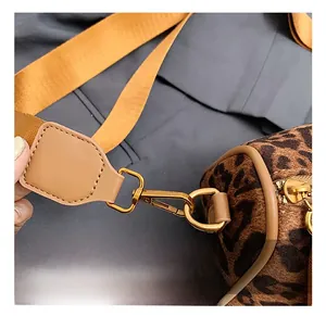 Close-up of golden metal hooks and wide strap on leopard print crossbody bag