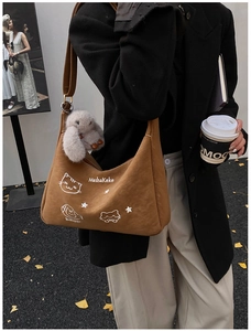 Detalle de bolso bandolera de pana marrón con bordado de gato y colgante de conejo