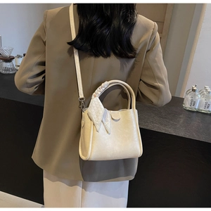Detail of cream leather bucket bag with silk scarf handle on a modern counter