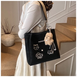 Dettaglio borsa tote in tela nera con grafica di gatto, catena argento e ciondolo peluche