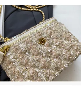 Détail d'un sac en tweed avec ornement floral doré et bandoulière en chaîne métallique