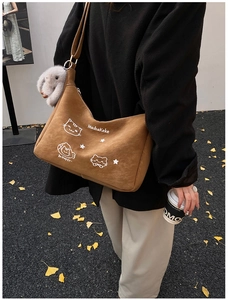 Detalle del bolso bandolera de ante marrón con bordado de gato y colgante de conejo