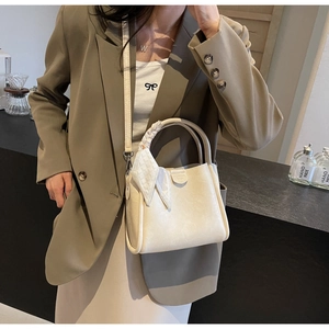 Chic beige bucket bag with decorative scarf-wrapped handle and slim shoulder strap detail