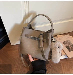 Dettaglio borsa a secchiello kaki con trama a grana e ciondolo a forma di coniglio