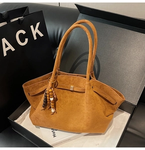 Detail of brown suede tote bag with wooden bead tassel and side buckle in gift box
